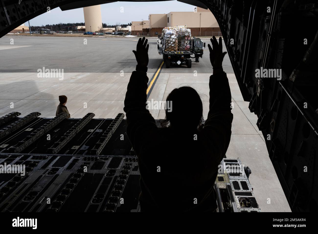 Senior Airman Josie Pitts, 758. Airlift Squadron Loader, leitet einen Airman, der der 32. Aerial Port Squadron zugewiesen ist und einen 25K Halverson Loader auf der Pittsburgh International Airport Air Reserve Station, Pennsylvania, am 16. Februar 2022 fährt. Der Halverson-Lader kann bis zu 25 kg Fracht aufnehmen und ermöglicht es den dem 32. APS zugewiesenen Flugzeugen, Fracht sicher und effektiv auf den C-17 Globemaster III zu transportieren und zu laden Stockfoto