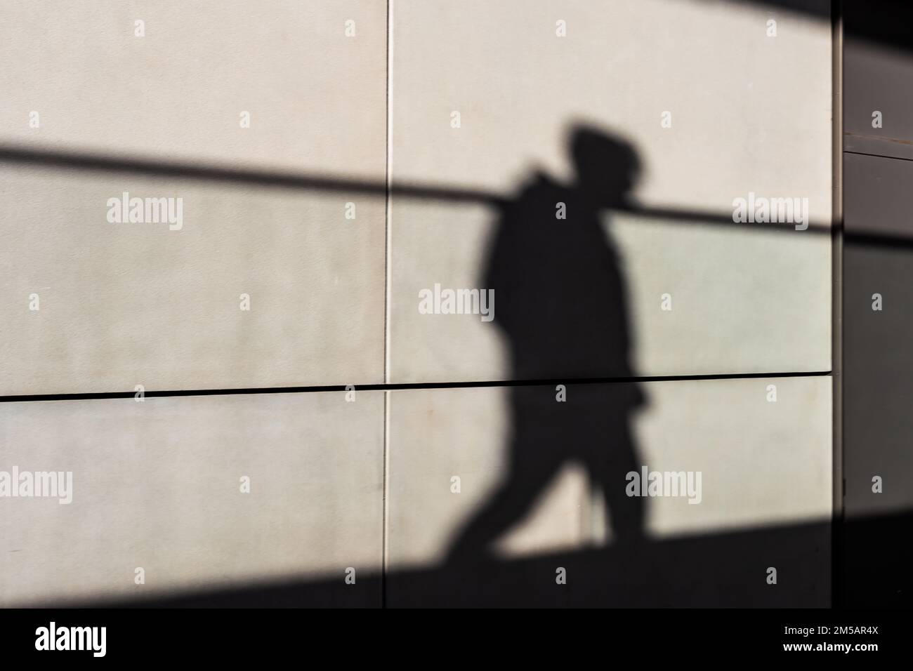 Eine schattige Figur, die über einen Gehweg in Silhouette läuft. Ein starkes Bild mit einem Konzept des ' Schatten seines früheren selbst ! ' Stockfoto