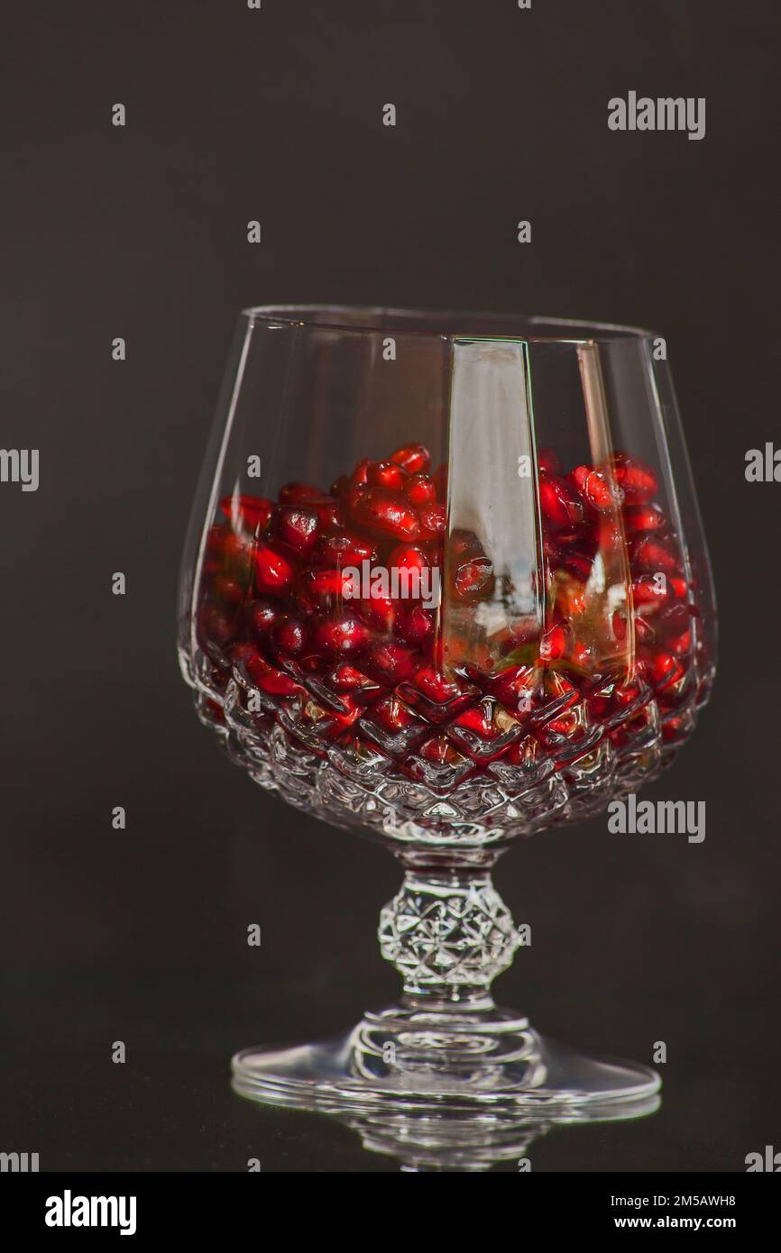 Noch lebend aus einem einschneidenden Kristallglas gefüllt mit glänzenden Granatapfelsamen. Stockfoto Noch lebend aus einem einschneidenden Kristallglas gefüllt mit glänzenden Granatapfelsamen. Stockfoto