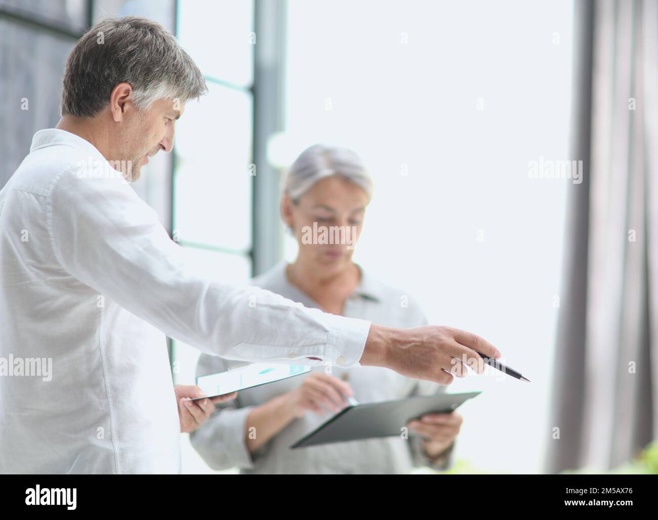 Geschäftsmann zeigt etwas zu reifen Geschäftsfrau durch gesehen Stockfoto