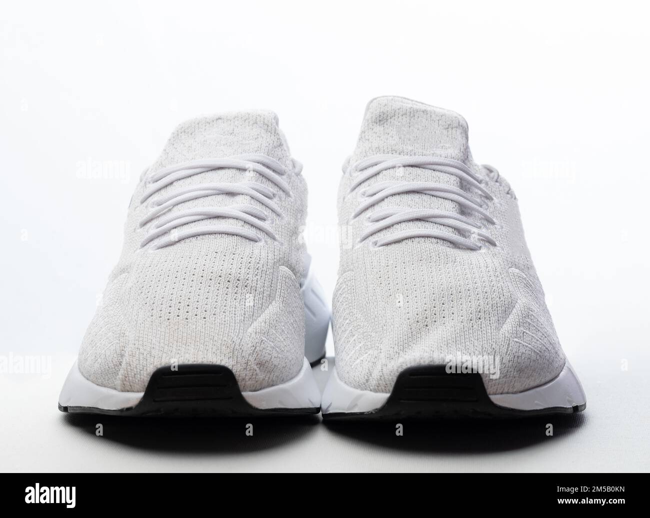 Vorderansicht von weißen Sportschuhen isoliert im Studiohintergrund Stockfoto