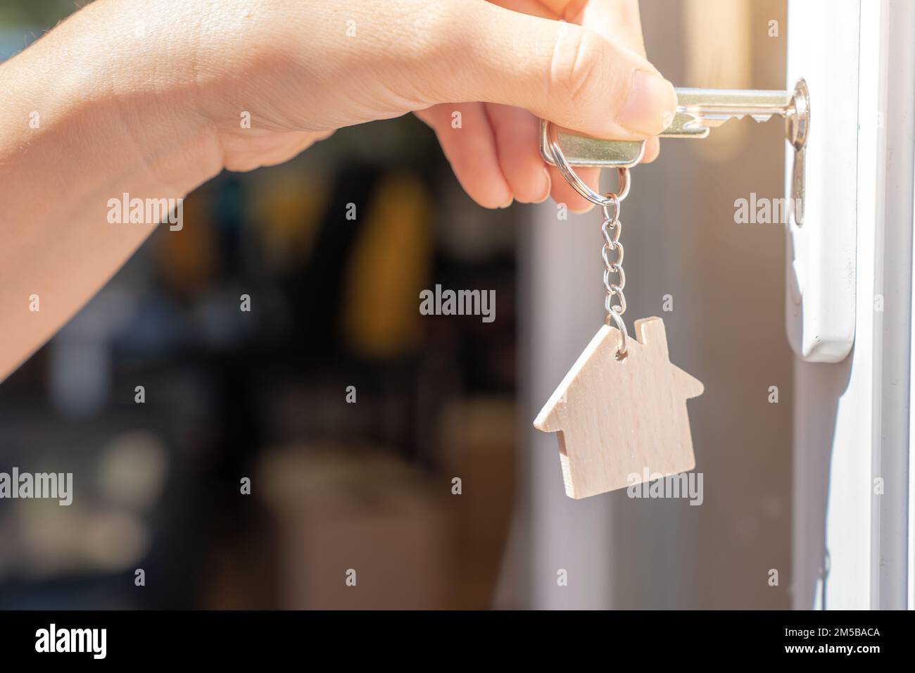 Öffnen Sie die Tür zu einem neuen Zuhause mit Schlüssel und Schlüsselanhänger in Form eines Hauses. Immobilien und neues Hauskonzept Stockfoto