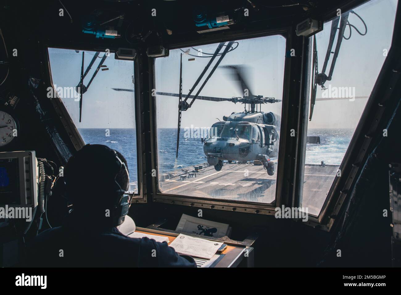 220222-N-GF955-1002 KARIBISCHES MEER - (21. Februar 2022) -- Boatswain’s Mate 1. Klasse Emmanuel Dixon zugeordnet zum Freiheitsvarianten-Küstenkampfschiff USS Billings (LCS 15) beobachtet vom Flugkontrollturm aus als MH-60s Sea Hawk Hubschrauber, der dem ‚Shadow Det‘ des Hubschraubers Sea Combat Squadron (HSC) 28, Einheit 7, startet vom Flugdeck, 21. Februar 2022. Billings wird in das US-Flottengebiet 4. entsandt, um die Mission der Joint Interagency Task Force South zu unterstützen, zu der auch Missionen zur Bekämpfung des illegalen Drogenhandels in der Karibik und im östlichen Pazifik gehören. Stockfoto