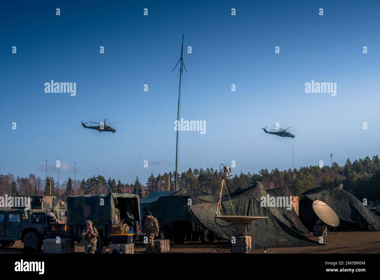 Die polnischen Hubschrauber Mi-24 Hind umkreisen das Feld und üben während der Übung Saber Strike 22 auf der BPTA (Polen) am 24. Februar 2022 die US-amerikanischen und polnischen Luftabwehreinheiten. In dieser Woche baut das 5-4. Bataillon der ADA Kapazitäten und Interoperabilität mit seinen polnischen Gegenstücken der Luftabwehr auf, indem es Daten zwischen alliierten Radargeräten und Waffenplattformen ausgibt und gleichzeitig Ziele im Feld verfolgt. Die Übung läuft bis März mit etwa 13.000 Teilnehmern aus 13 Ländern. Saber Strike findet seit 2010 alle 2 Jahre statt. USA Armeefoto von Major Robert Fellingham) Stockfoto