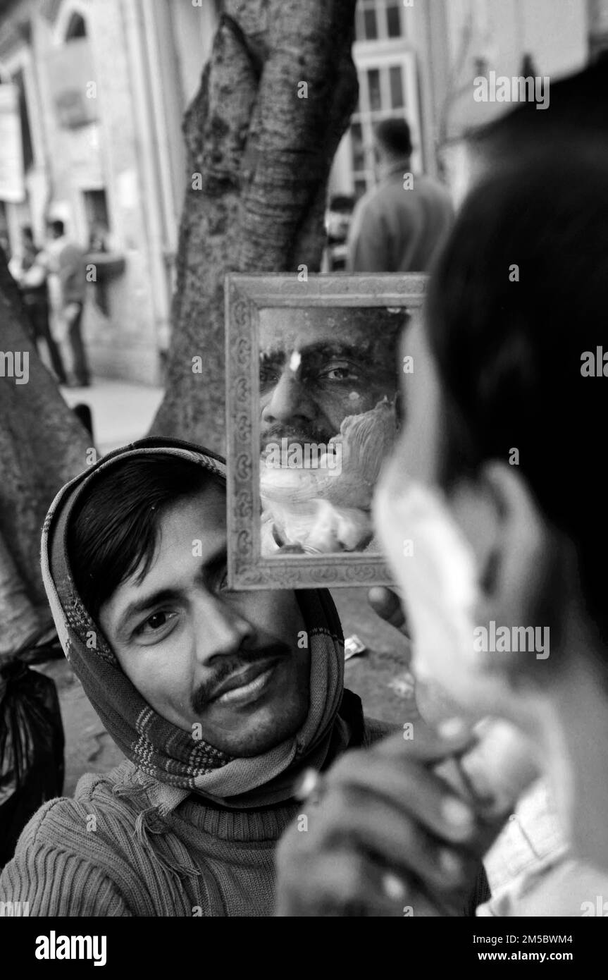 Ein Straßenfriseur rasiert einen Mann in Kalkutta, Indien. Stockfoto