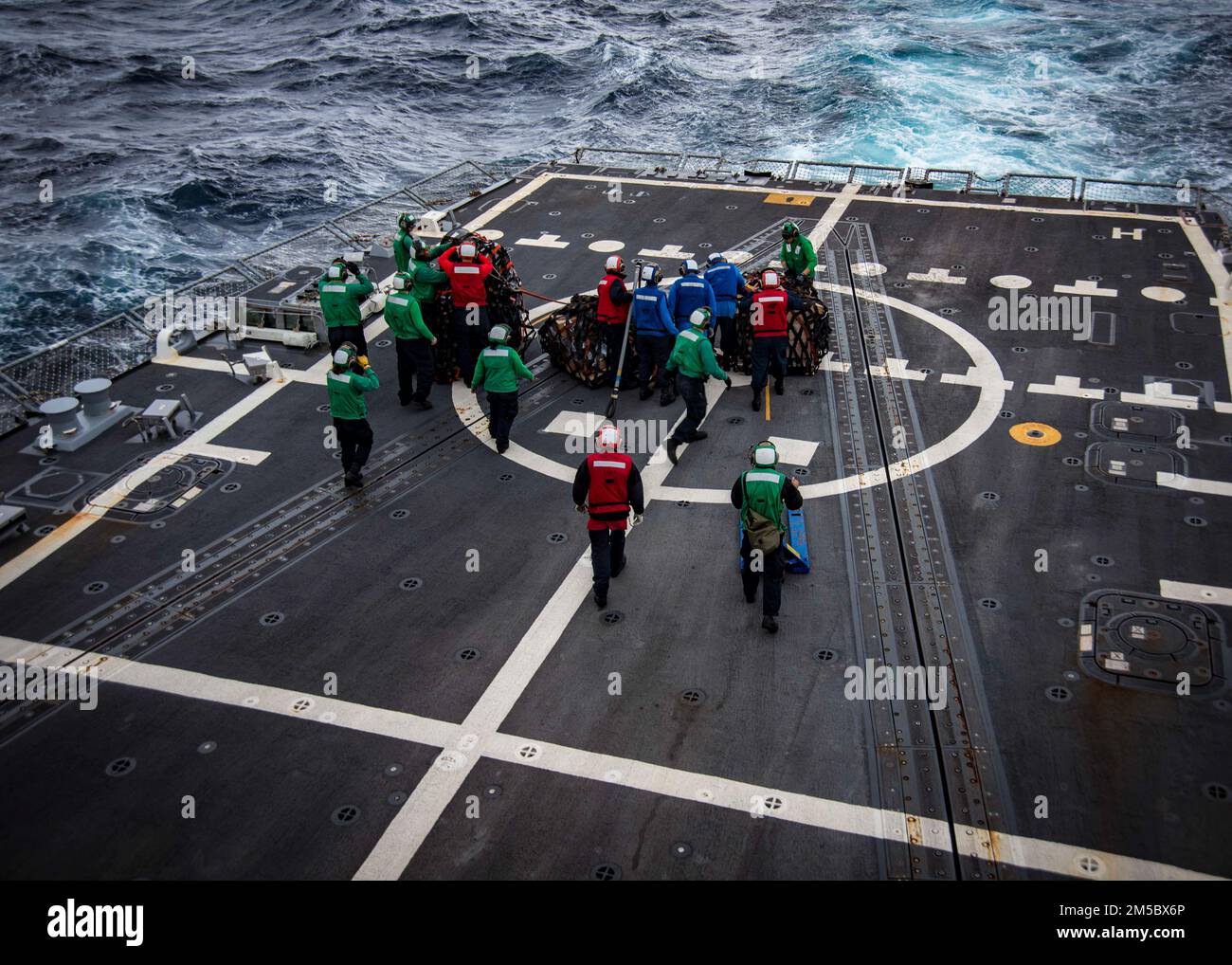 Matrosen an Bord des Zerstörers USS Delbert D. Black (DGG 119) brechen während einer vertikalen Nachschub mit dem Nachschuböler USNS John Lenthall (T-AO-189) Vorräte auf, während sie auf dem Weg zum Surface Warfare Advanced Tactical Training (SWATT) sind. Delbert D. Black ist Teil der Destroyer Squadron (DESRON) 26, die die Carrier Strike Group (CSG) 10 unterstützt. SWATT wird vom Naval Surface and Mine Warfighting Development Center (SMWDC) geleitet und soll die Kampffähigkeit, die Letalität und die Interoperabilität der teilnehmenden Einheiten verbessern. Stockfoto