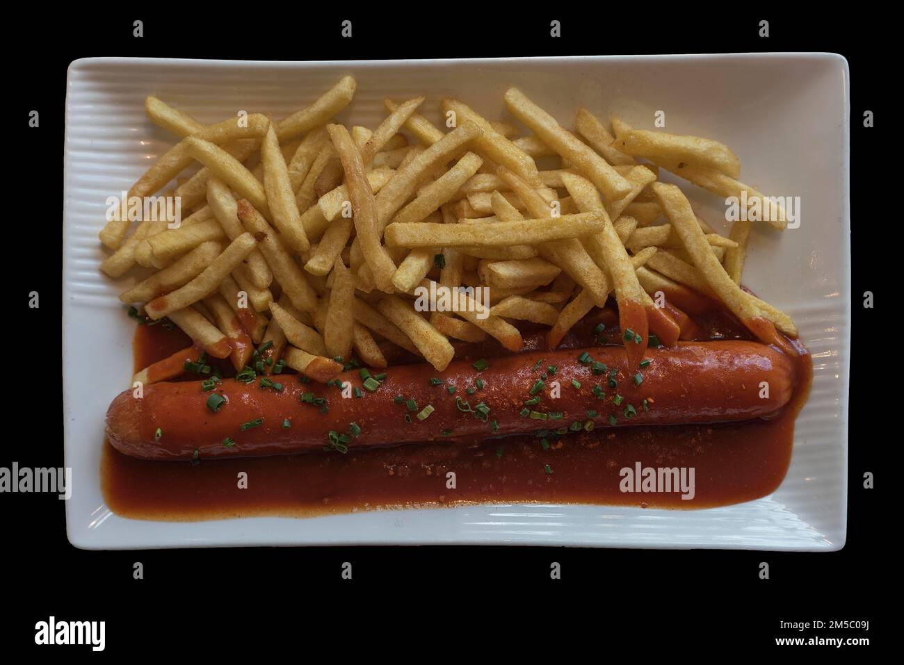 Currywurst mit pommes frites auf weißem Teller, schwarzer Hintergrund, Bayern, Deutschland Stockfoto