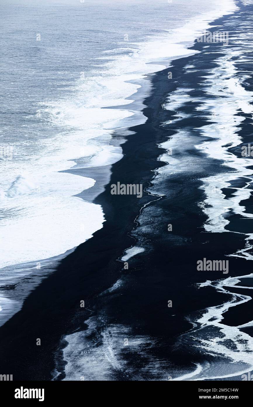 Schäumende weiße Wellen und eisige Oberflächen am schwarzen Kieselstrand Skogarsandur, in der Nähe von Dyrholaey, Sudurland, Island Stockfoto
