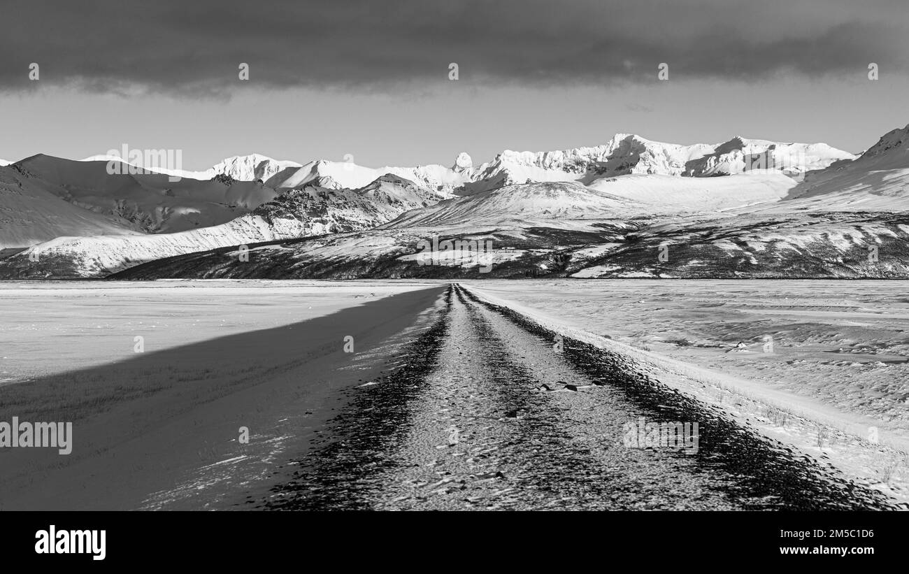 Unbefestigte Straße in Richtung der schneebedeckten Berge von Skaftefellsjoell, Schwarzweißfoto, in der Nähe von Skaftafell, Sudurland, Island Stockfoto