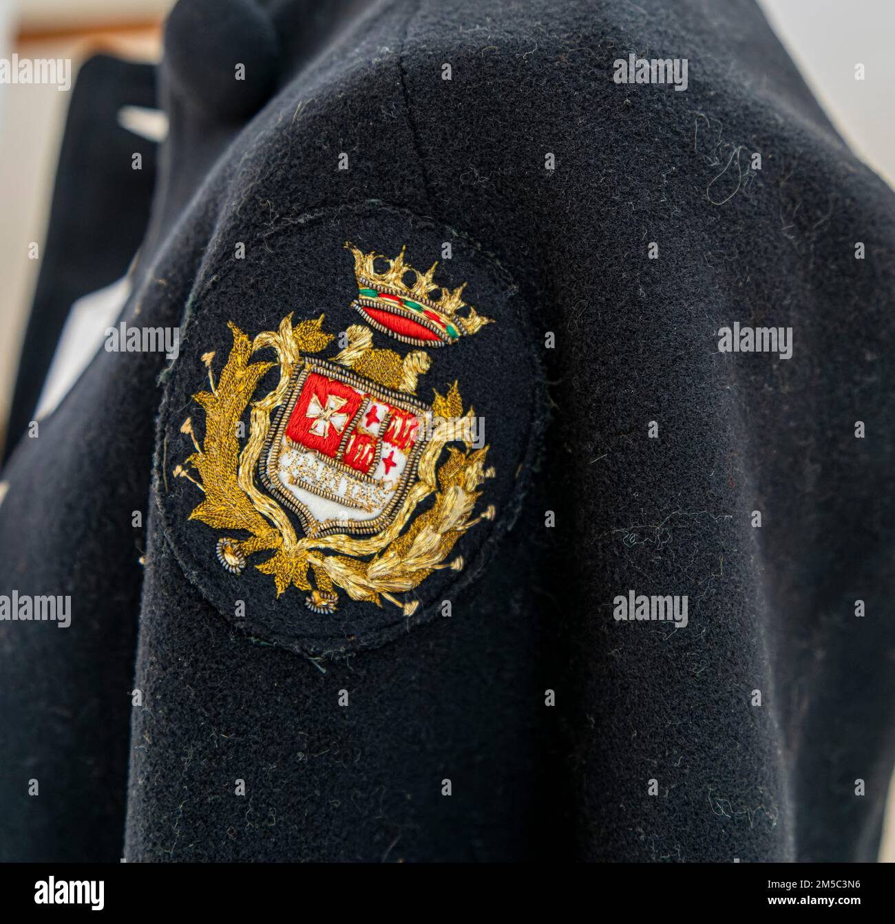 Wappen auf einer historischen Uniform des Krankenpflegepersonals im ehemaligen Krankenhauskomplex des Hospital de la Santa Creu i Sant Pau, Barcelona Stockfoto