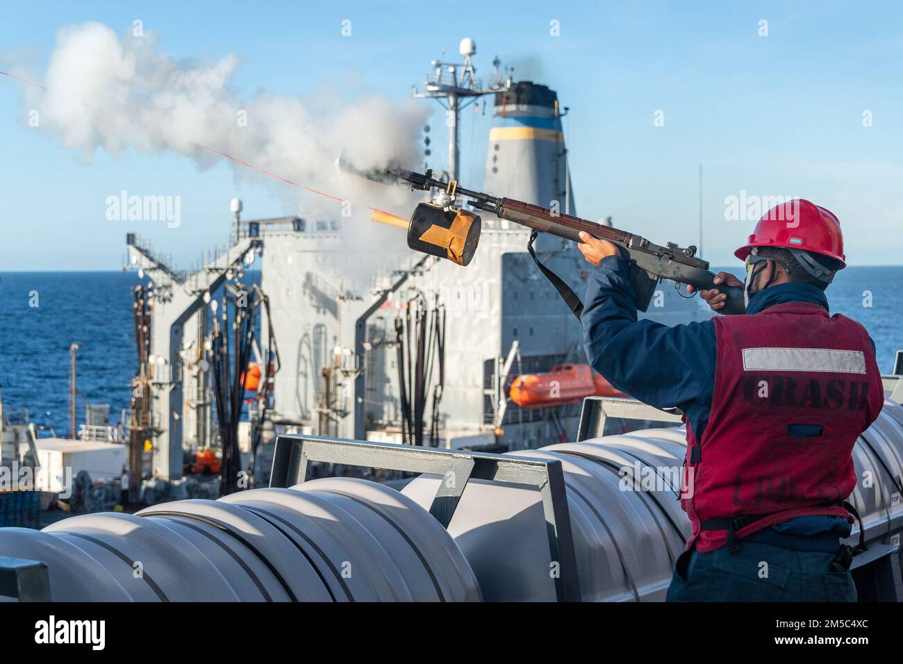 220227-N-VQ947-1052 PAZIFIK (27. FEBRUAR 2022) — Gunner's Mate 3. Class Brandon Watkins, aus Chesterton, Ind., feuert eine Botenlinie vom Amphibiendock der San Antonio-Klasse USS Portland (LPD 27) zum Henry J. Kaiser-Klasse-Nachfüllöler USNS Pecos (T-AO 197), Hintergrund, während einer Wiederauffüllung auf See im Pazifischen Ozean, 27. Februar 2022. Matrosen und Marines der Essex Amphibious Ready Group (ARG) und der 11. Marine Expeditionary Unit (MEU) führen derzeit Routineeinsätze in der US-3.-Flotte durch. Stockfoto