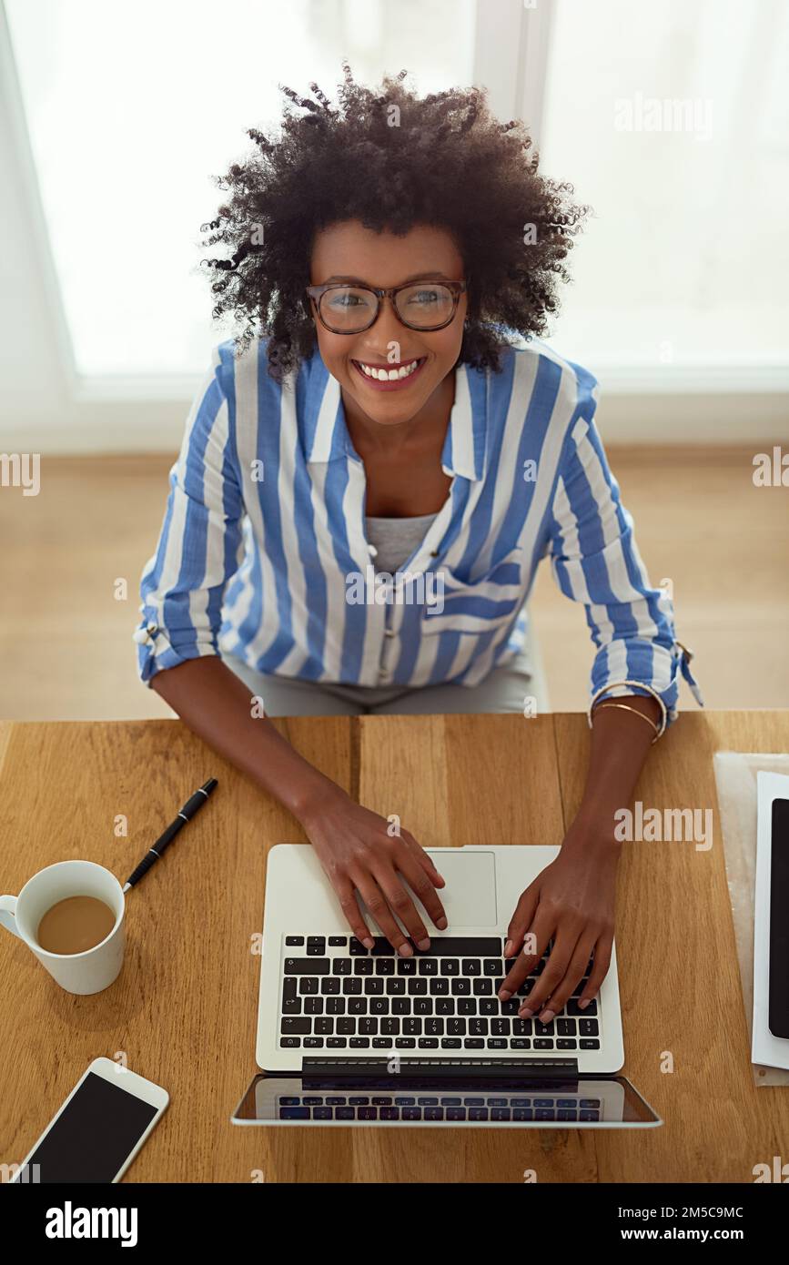 Mein neuester Blogbeitrag wird sicher ein Hit sein. Porträt einer jungen Frau, die zu Hause an ihrem Laptop arbeitet. Stockfoto