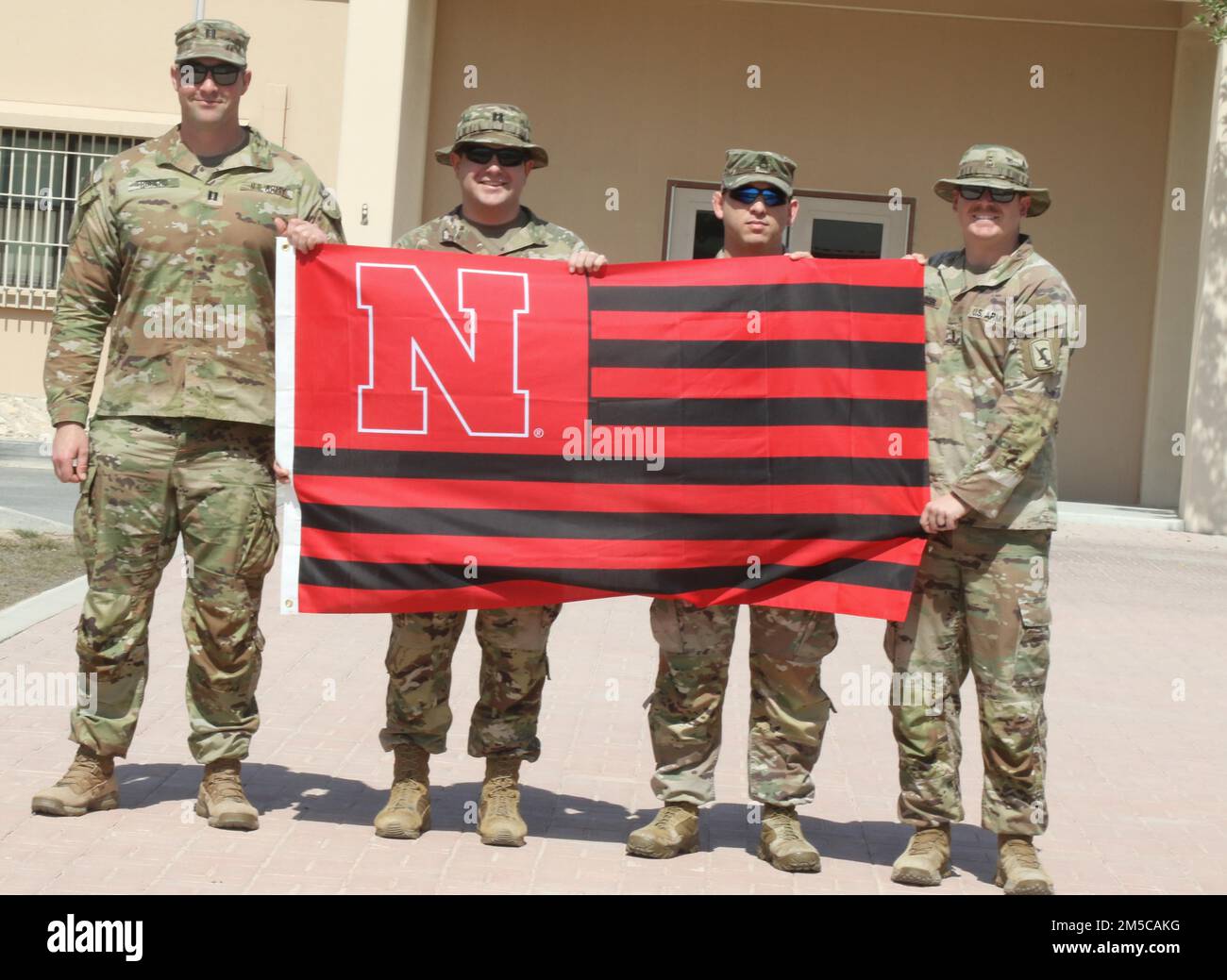 Entsandte Soldaten der Nationalgarde Nebraska, die dem 734. Kampfstützungsbataillon zugewiesen sind und derzeit dem Hilfswerk der afghanischen Evakuierungsmission helfen, fliegen anlässlich des 155. Jahrestages der Staatlichkeit am 1. März 2022 im Camp AS Saliyah, Katar, unter der Flagge der Universität Nebraska. Nebraska wurde 1867 in die Gewerkschaft aufgenommen. Seither hat die Nationalgarde eine wesentliche Rolle bei der Bereitstellung von Katastrophenhilfe und bei der Beantwortung des nationalen Aufrufs während bewaffneter Konflikte gespielt. Im Camp AS Sayliyah sind die Kearney-Soldaten Teil der größten Evakuierungsoperation Sünde Stockfoto