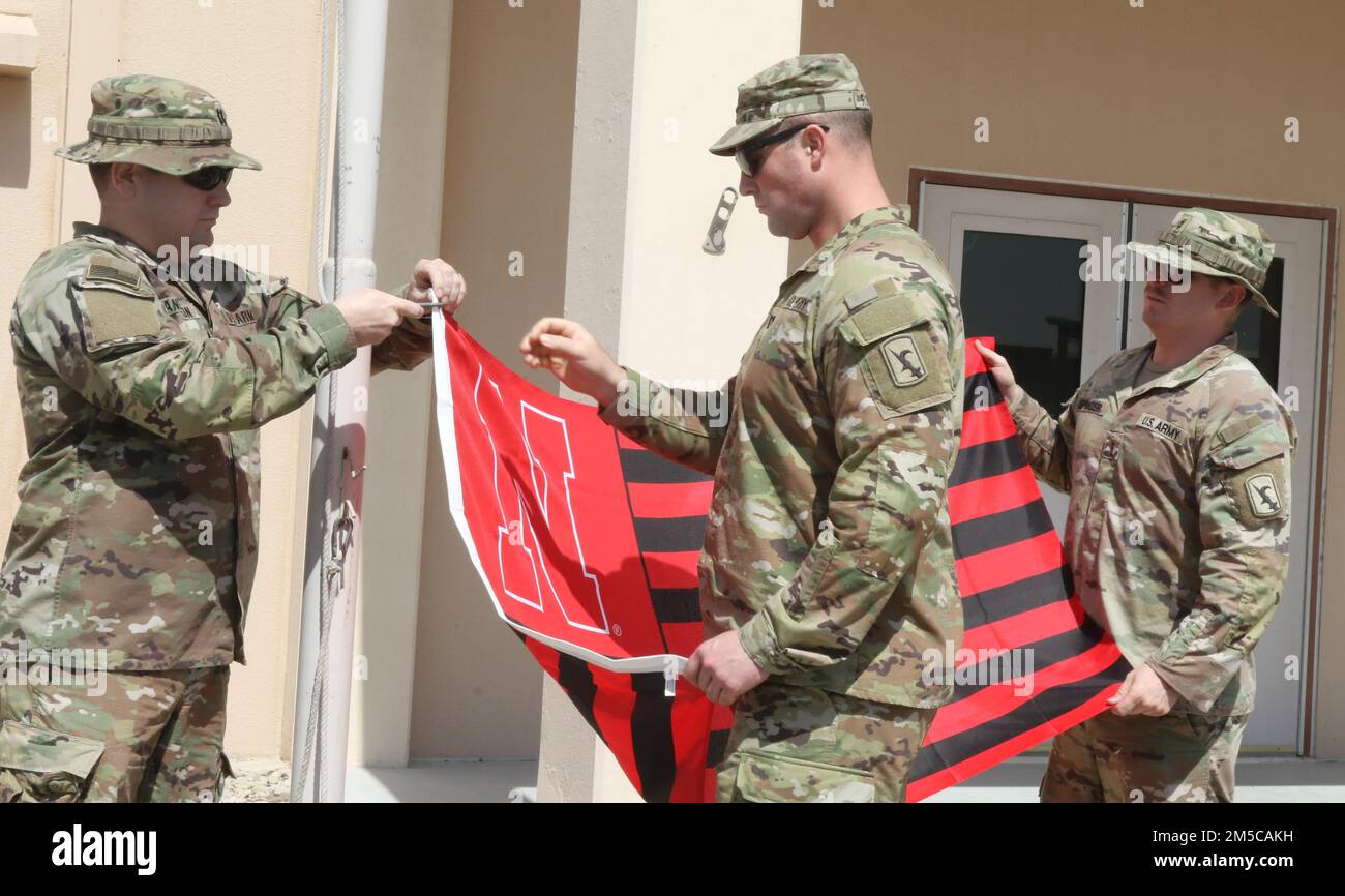 Entsandte Soldaten der Nationalgarde Nebraska, die dem 734. Kampfstützungsbataillon zugewiesen sind und derzeit dem Hilfswerk der afghanischen Evakuierungsmission helfen, fliegen anlässlich des 155. Jahrestages der Staatlichkeit am 1. März 2022 im Camp AS Saliyah, Katar, unter der Flagge der Universität Nebraska. Nebraska wurde 1867 in die Gewerkschaft aufgenommen. Seither hat die Nationalgarde eine wesentliche Rolle bei der Bereitstellung von Katastrophenhilfe und bei der Beantwortung des nationalen Aufrufs während bewaffneter Konflikte gespielt. Im Camp AS Sayliyah sind die Kearney-Soldaten Teil der größten Evakuierungsoperation Sünde Stockfoto