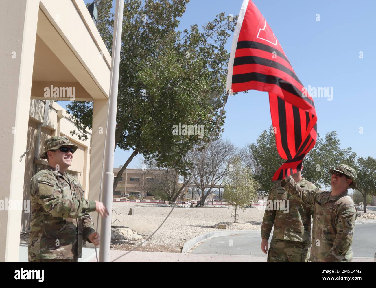 Entsandte Soldaten der Nationalgarde Nebraska, die dem 734. Kampfstützungsbataillon zugewiesen sind und derzeit dem Hilfswerk der afghanischen Evakuierungsmission helfen, fliegen anlässlich des 155. Jahrestages der Staatlichkeit am 1. März 2022 im Camp AS Saliyah, Katar, unter der Flagge der Universität Nebraska. Nebraska wurde 1867 in die Gewerkschaft aufgenommen. Seither hat die Nationalgarde eine wesentliche Rolle bei der Bereitstellung von Katastrophenhilfe und bei der Beantwortung des nationalen Aufrufs während bewaffneter Konflikte gespielt. Im Camp AS Sayliyah sind die Kearney-Soldaten Teil der größten Evakuierungsoperation Sünde Stockfoto