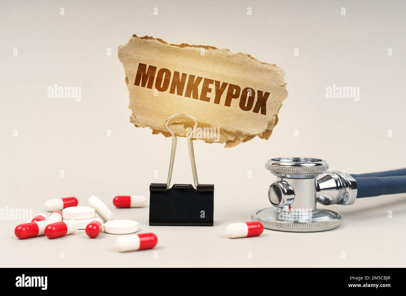 Medizinisches Konzept. In der Nähe des Stethoskops sind Pillen und ein Clip mit einem Pappschild - Affen-Pocken Stockfoto