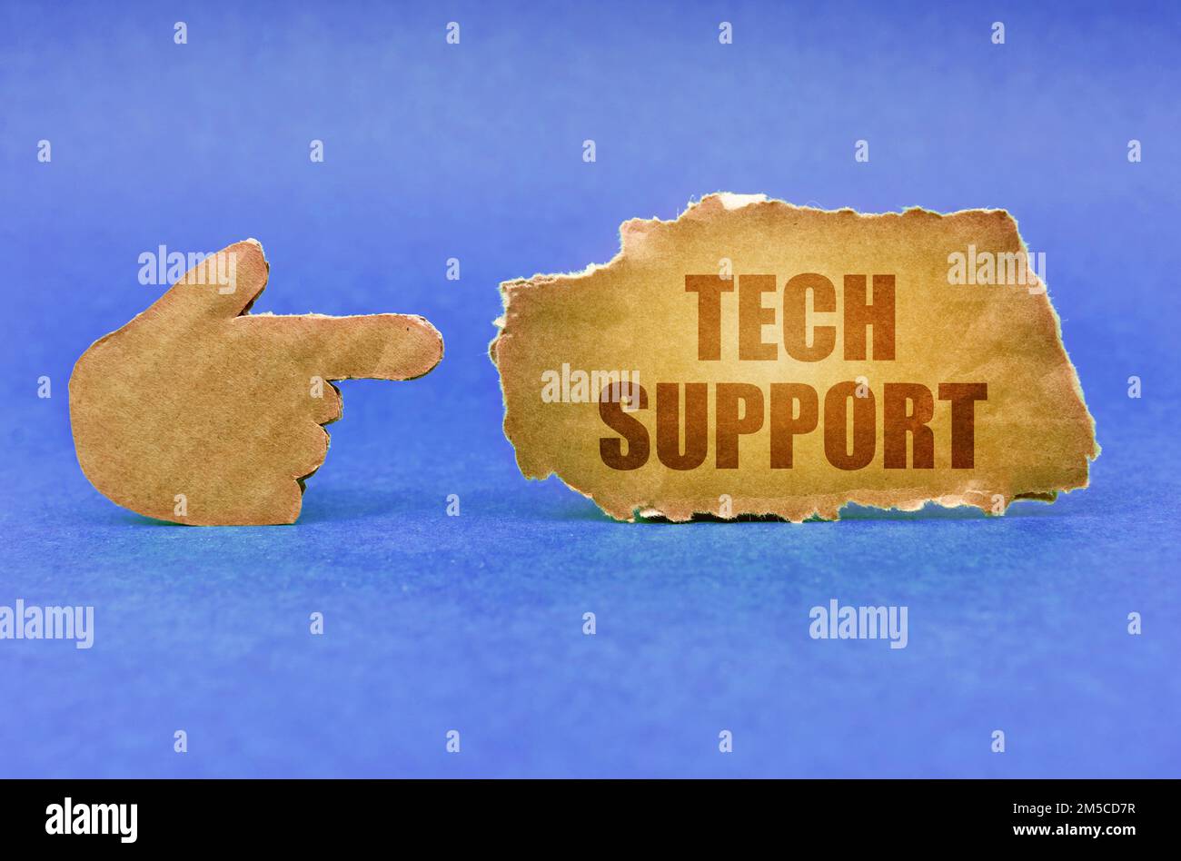 Technologisches Konzept. Auf einer blauen Oberfläche zeigt eine Kartonhand auf ein Schild mit der Aufschrift „Technischer Support“ Stockfoto