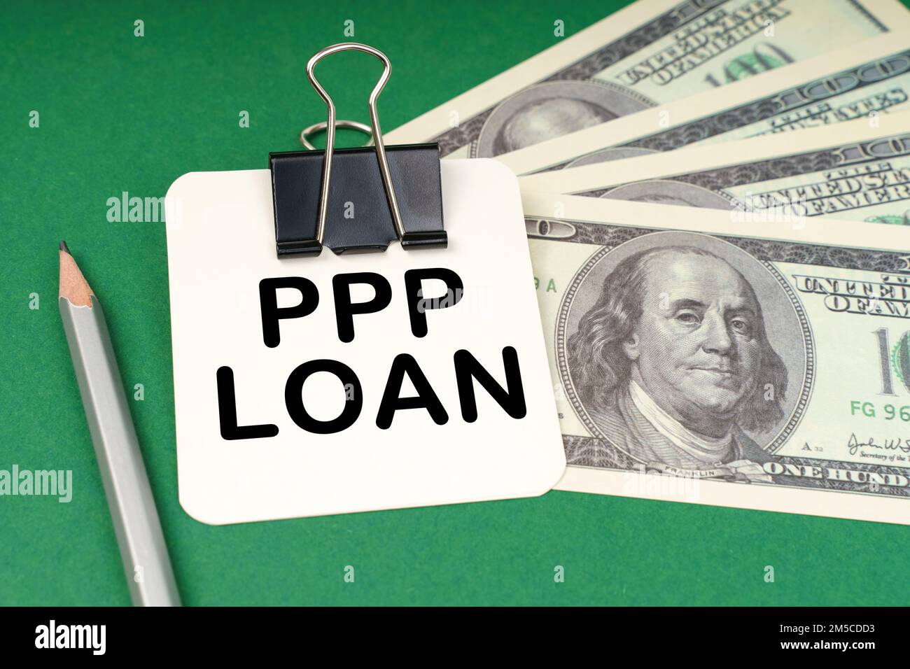 Geschäftskonzept. Auf einer grünen Oberfläche, einem Stift, Dollars und in einem Heftpapier mit der Aufschrift "PPP-Kredit" Stockfoto