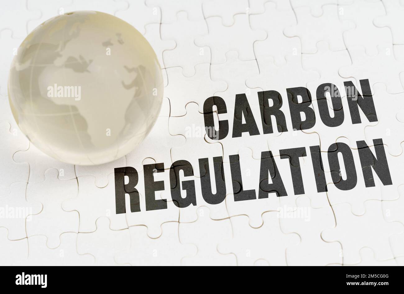Ökologisches Konzept. Auf weißen Rätseln gibt es eine Glaskugel und die Inschrift - Kohlenstoff-Regelung Stockfoto
