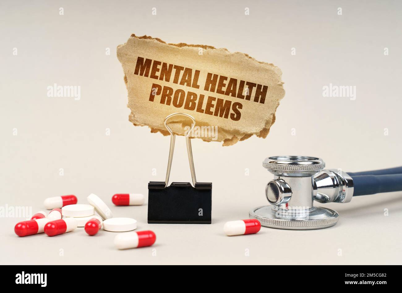 Medizinisches Konzept. In der Nähe des Stethoskops sind Pillen und ein Clip mit einem Pappschild - psychische Gesundheitsprobleme Stockfoto