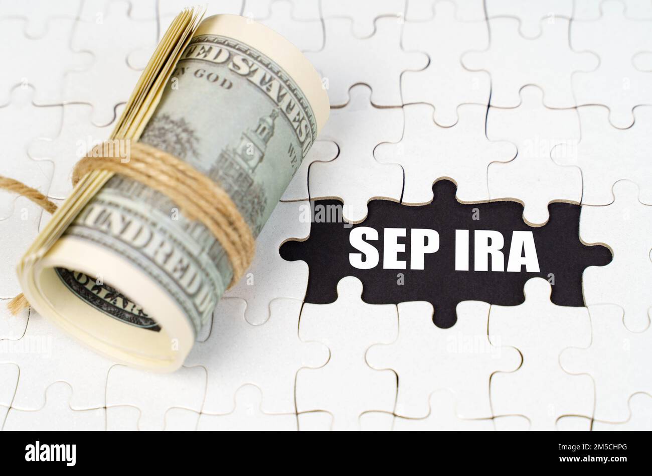 Geschäftskonzept. Dollars liegen auf weißen Rätseln, auf einer schwarzen Oberfläche ist eine Inschrift - SEP IRA Stockfoto Geschäftskonzept. Dollars liegen auf weißen Rätseln, auf einer schwarzen Oberfläche ist eine Inschrift - SEP IRA Stockfoto