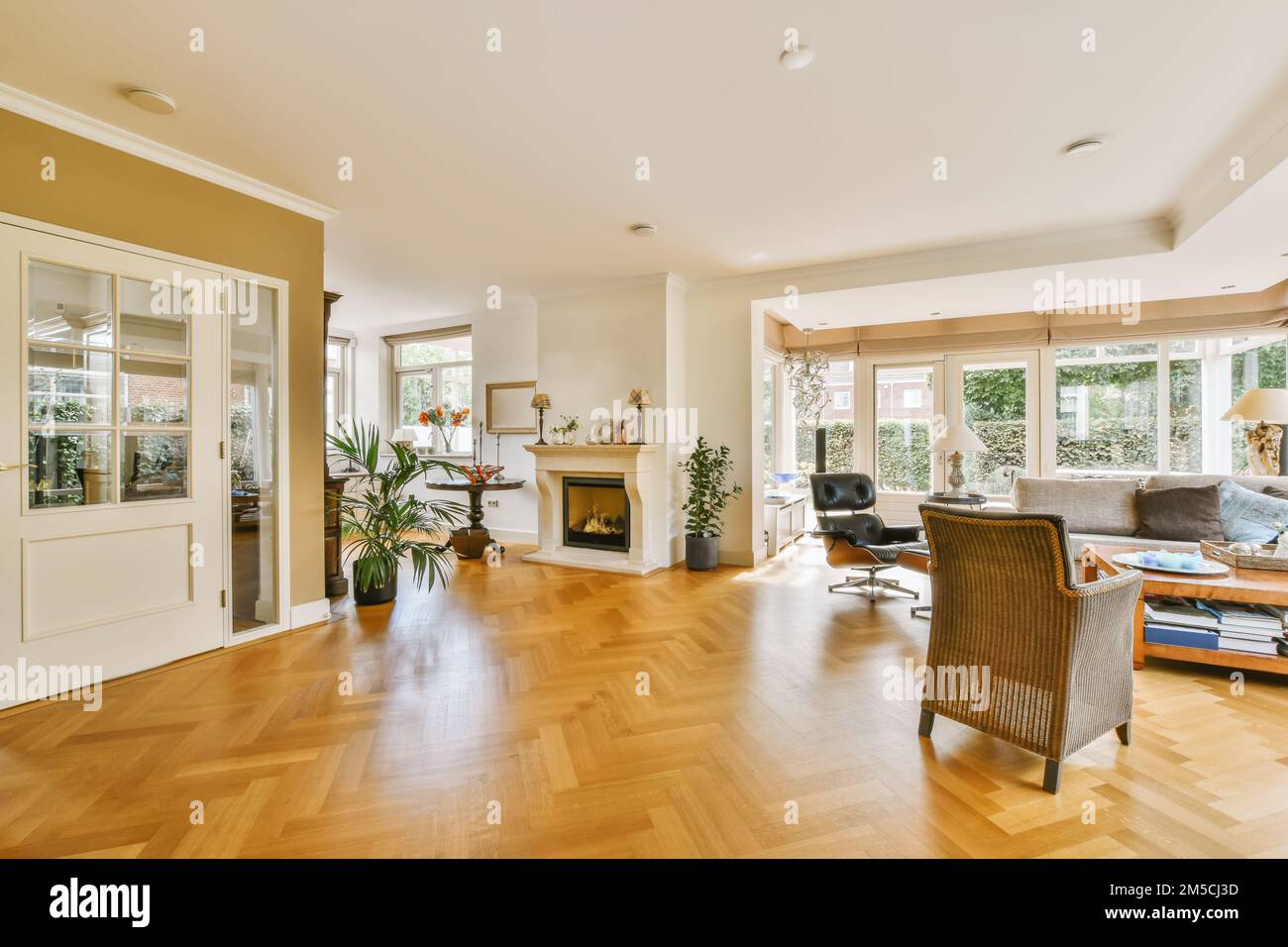 Ein Wohnzimmer mit Holzfußboden und weißen Verzierungen an den Wänden, es gibt einen Kamin in der Ecke Stockfoto