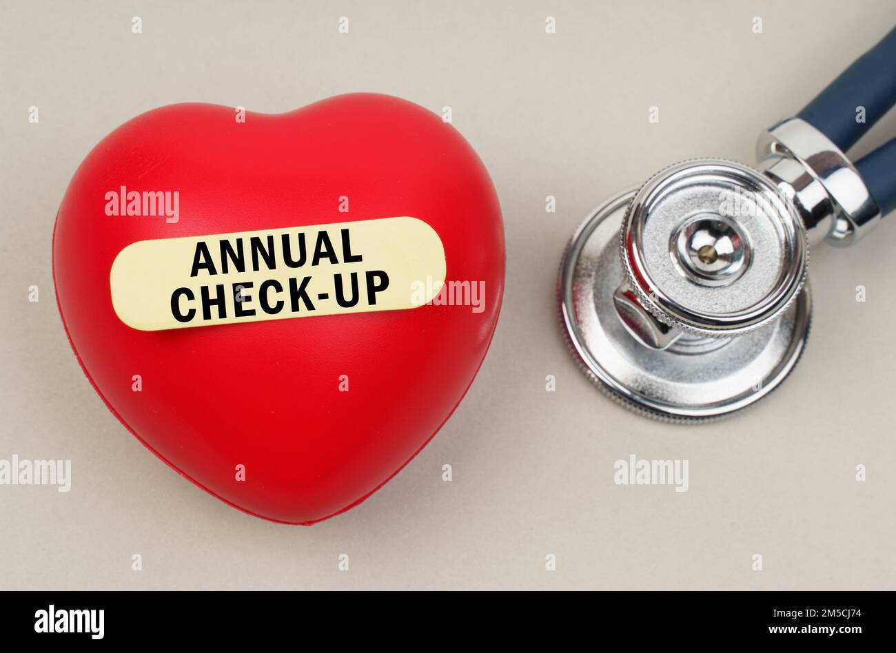Medizinisches Konzept. In der Nähe des Stethoskops liegt ein Herz, auf dem ein Aufkleber mit der Aufschrift angebracht wird - JÄHRLICHE KONTROLLE Stockfoto