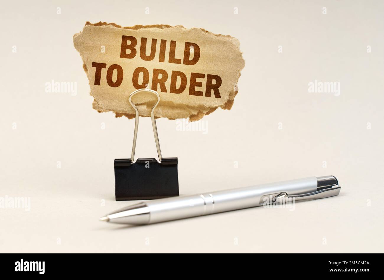 Industrie- und Geschäftskonzept. Neben dem Griff befindet sich ein Büroclip mit einem Schild. Auf dem Schild befindet sich die Aufschrift „Build to Order“ Stockfoto