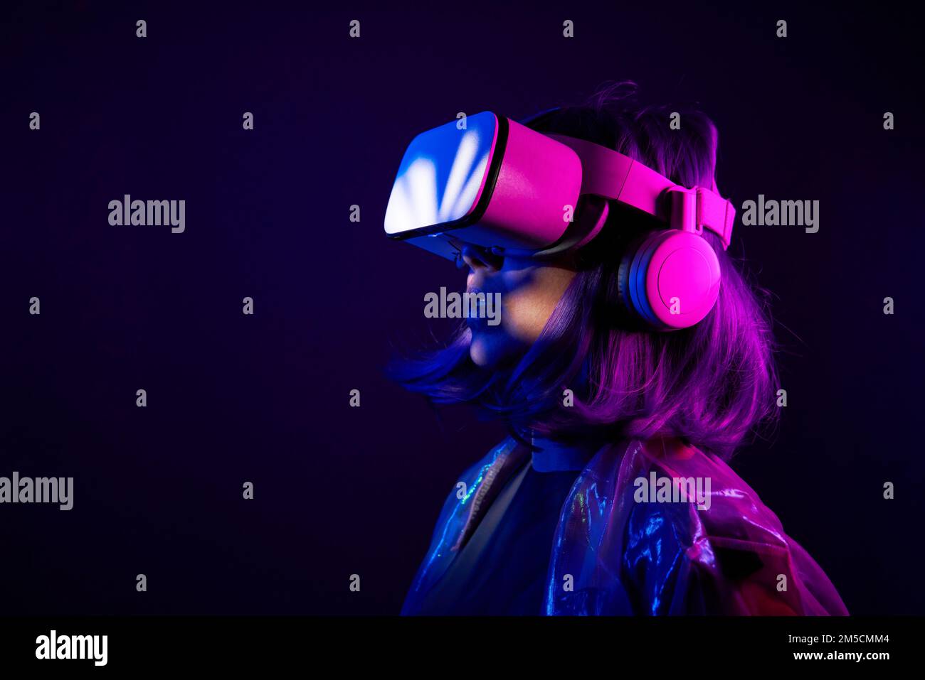 Eine Frau in Virtual-Reality-Brille in Neonfarben. Das Konzept der digitalen Technologie für Metaversum und Unterhaltung der Zukunft. Stockfoto