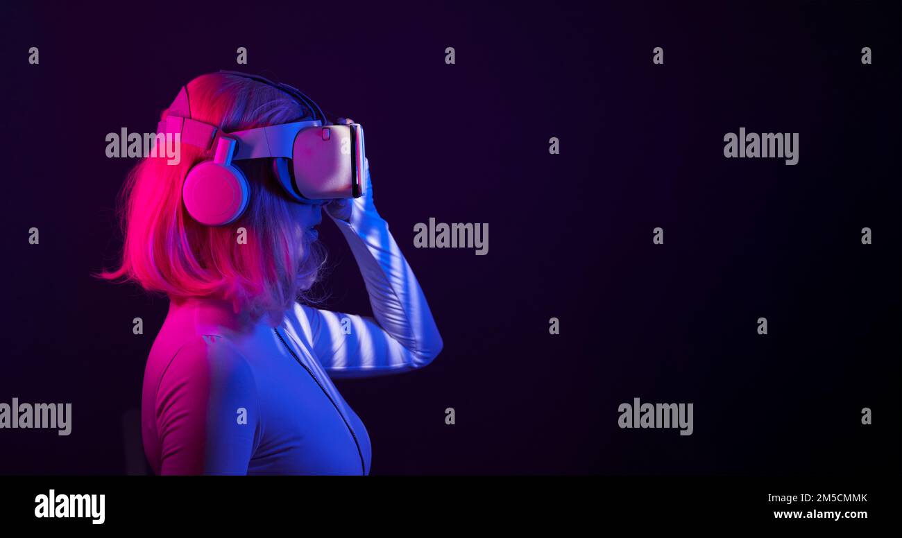 Eine Frau in Virtual-Reality-Brille in Neonfarben. Das Konzept der digitalen Technologie für Metaversum und Unterhaltung der Zukunft. Stockfoto