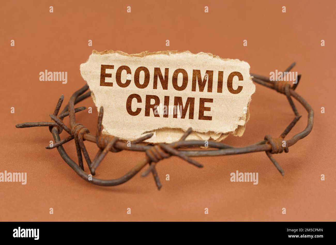 Der Begriff von Recht und Verbrechen. Auf einer braunen Oberfläche, Stacheldraht und ein Pappschild mit der Aufschrift "Wirtschaftskriminalität" Stockfoto