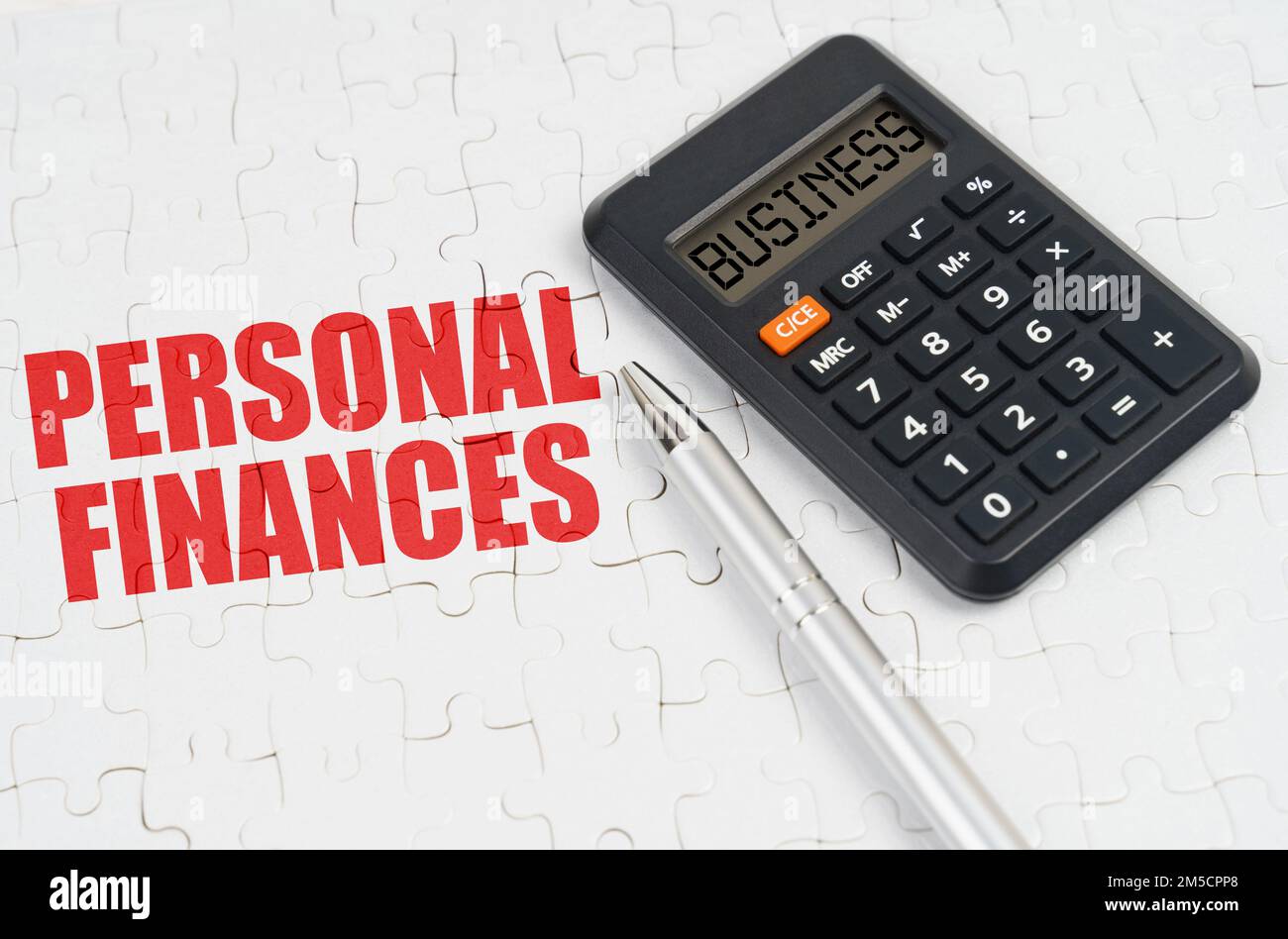 Geschäftskonzept. Auf den Rätseln liegen ein Rechner und ein Stift, neben der Inschrift - Persönliche Finanzen Stockfoto