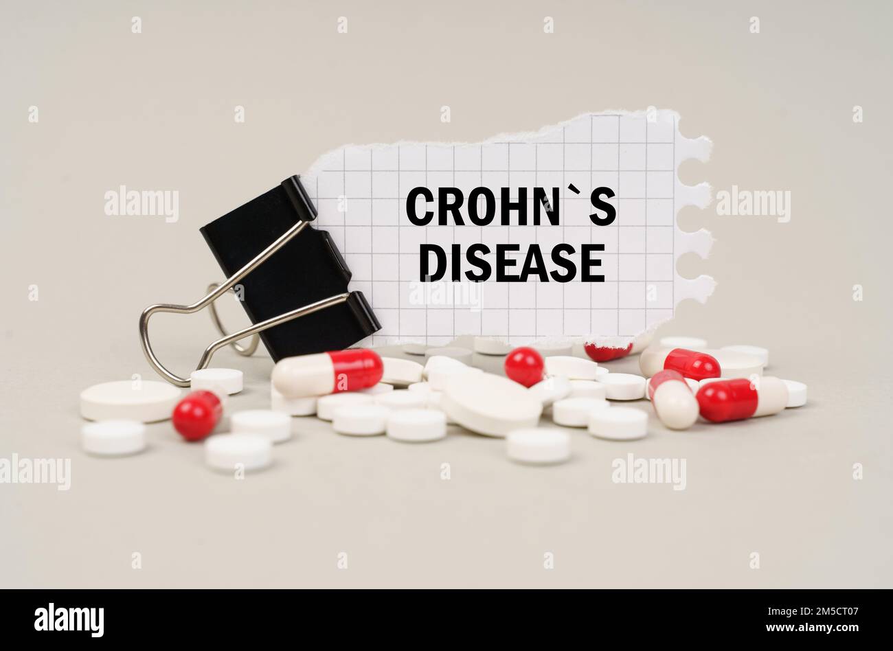 Medizinisches Konzept. Unter den Tabletten und Kapseln ist ein Clip mit Papier, auf dem geschrieben ist - CROHNS-KRANKHEIT Stockfoto