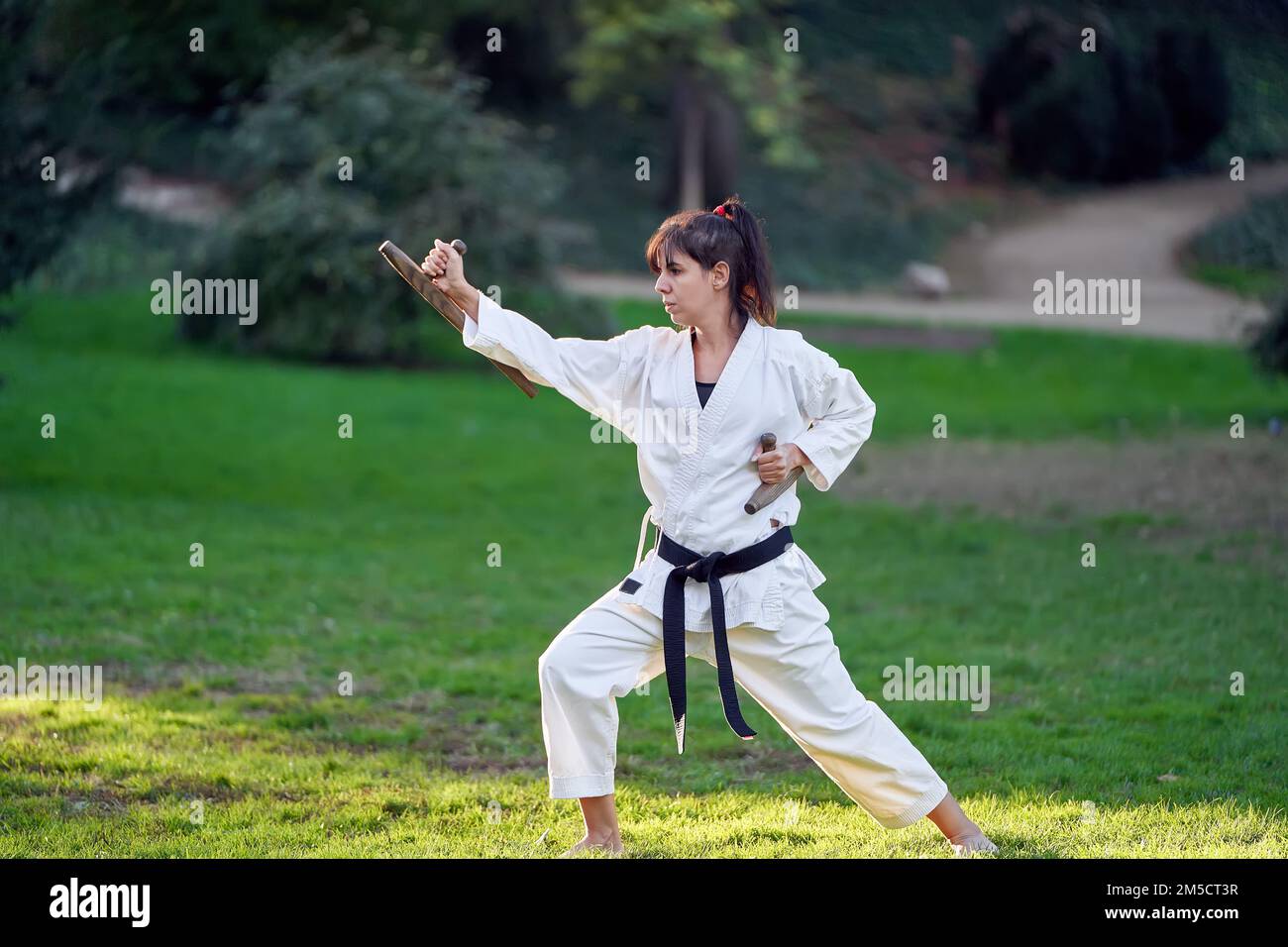 Karate-Kämpferin in weißem Kimono und Black-Belt-Training im Freien. Sport- und Kampfsportkonzept. Stockfoto