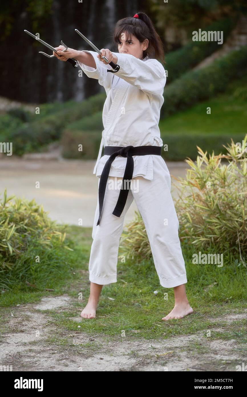 Karate-Kämpferin mit schwarzem Gürtel, die im Freien Karate in der Natur praktiziert. Sport- und Kampfsportkonzept. Stockfoto