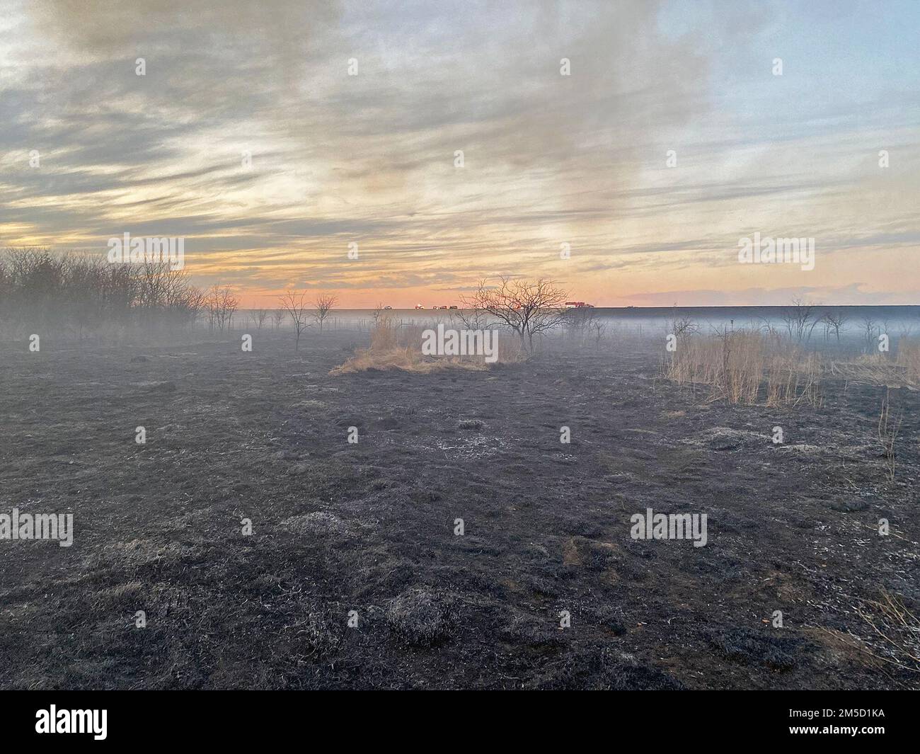 LEWISVILLE, Texas (2. März 2022) Feuerwehrleute und Partneragenturen kämpfen unter dem Lewisville Lake Dam gegen eine brennende Graslandfläche. Im Lewisville Lake Environmental Learning Area am Lewisville Lake wurde ein vorgeschriebenes Feuer ausgelöst, um Prärien unterhalb des Lewisville Dam zu erschaffen, wiederherzustellen und zu beleben. Man ging davon aus, dass dieser Brand vor 12 Uhr unter Kontrolle gebracht werden sollte, aber aufgrund von Wind- und Wetterveränderungen konnte der Brand aus dem vorgesehenen Bereich entweichen. Feuerwehrleute aus Flower Mound, Frisco und mehreren anderen umliegenden Städten reagierten auf gegenseitige Hilfeanfragen mit Bürstenwagen, um Conta zu helfen Stockfoto