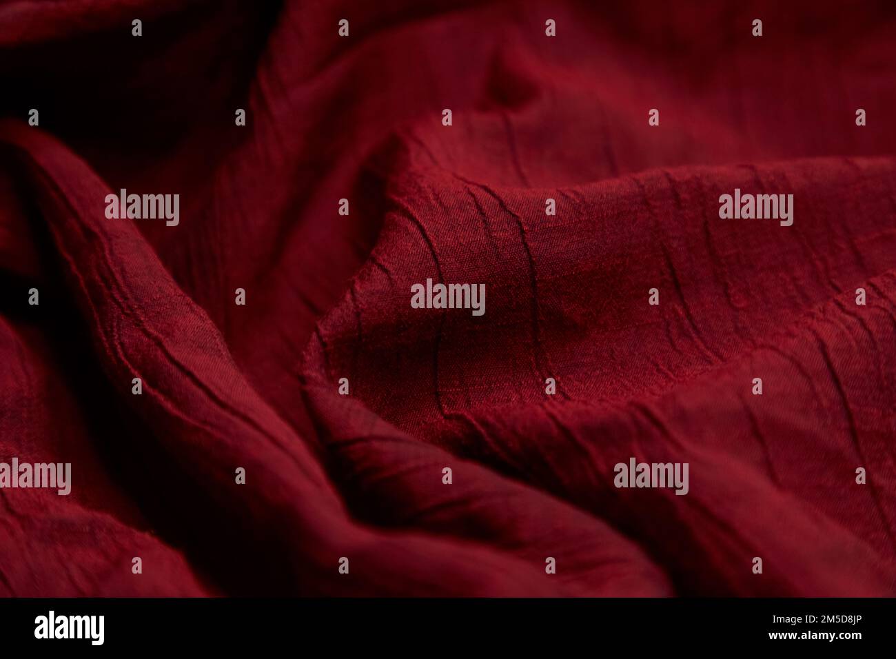 Verschwommener, roter Stoffhintergrund. Rotes Tuch Wellen Hintergrundstruktur. Rotes Stoffgewebe Textilmaterial. Stockfoto