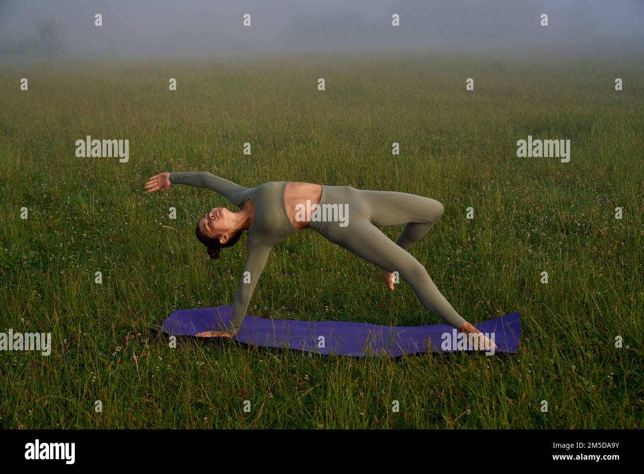Fitnessfrau in Sportbekleidung, die morgens Yoga an der frischen Luft übt. Junge weibliche Person führt einen gesunden und aktiven Lebensstil. Stockfoto