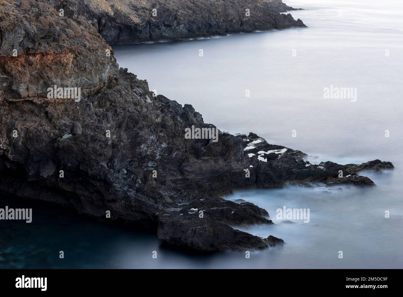 Langzeitaufnahme des Atlantiks, der sich um schroffe Vulkanfelsen an der Westküste von Teneriffa, Kanarische Inseln, Spanien, dreht Stockfoto