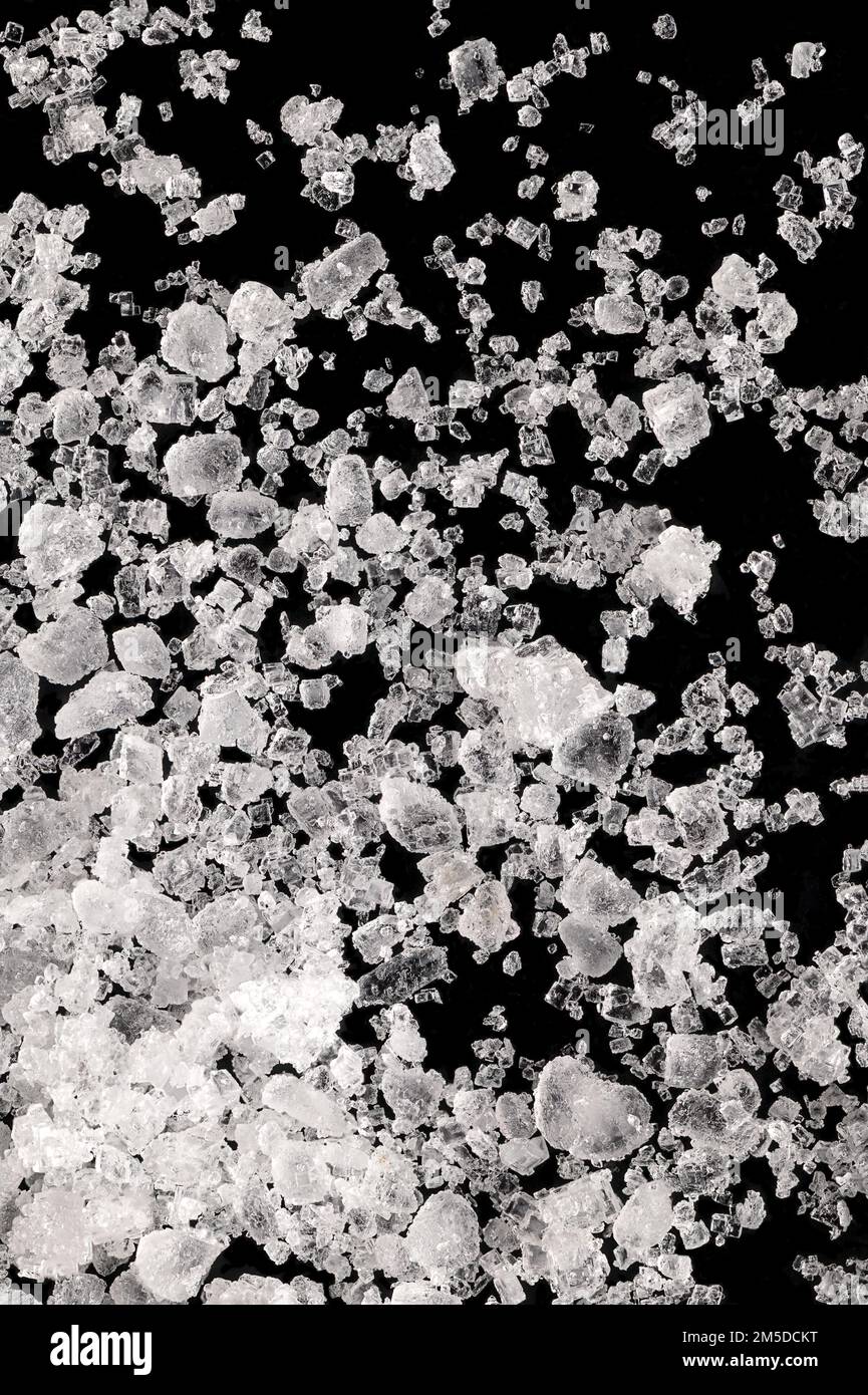 Meersalz, Flour de sel, Nahaufnahme von Kristallen auf einer schwarzen Oberfläche. Außerdem flor de Sal, ein Salz, das eine dünne empfindliche Kruste auf verdampfendem Meerwasser bildet. Stockfoto