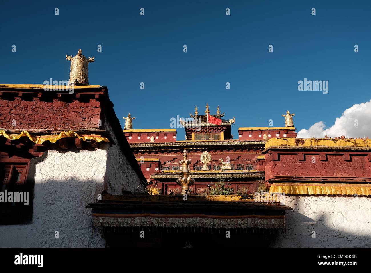 Tibetische Architektur. Traditionelles tibetisches Haus im Sonnenlicht und blauem Himmel mit Wolkenhintergrund. Haus mit Ornamenten in der Provinz Sichuan, China. Stockfoto