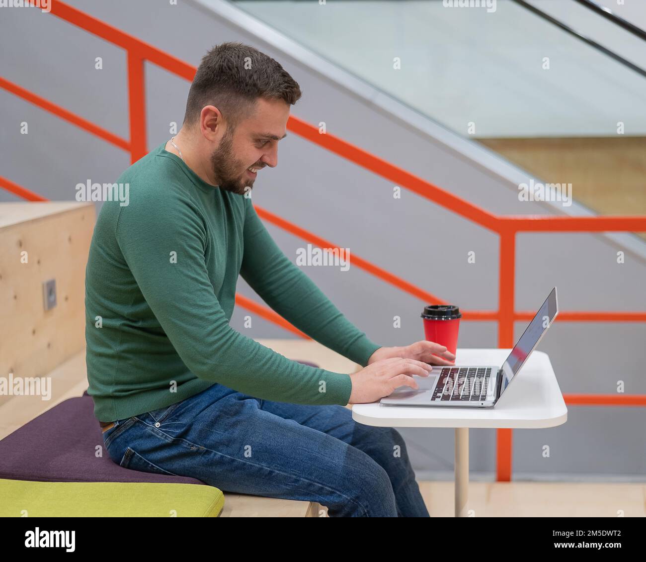 Ein weißer Mann, der an einem Laptop arbeitet. Offener Raum. Stockfoto