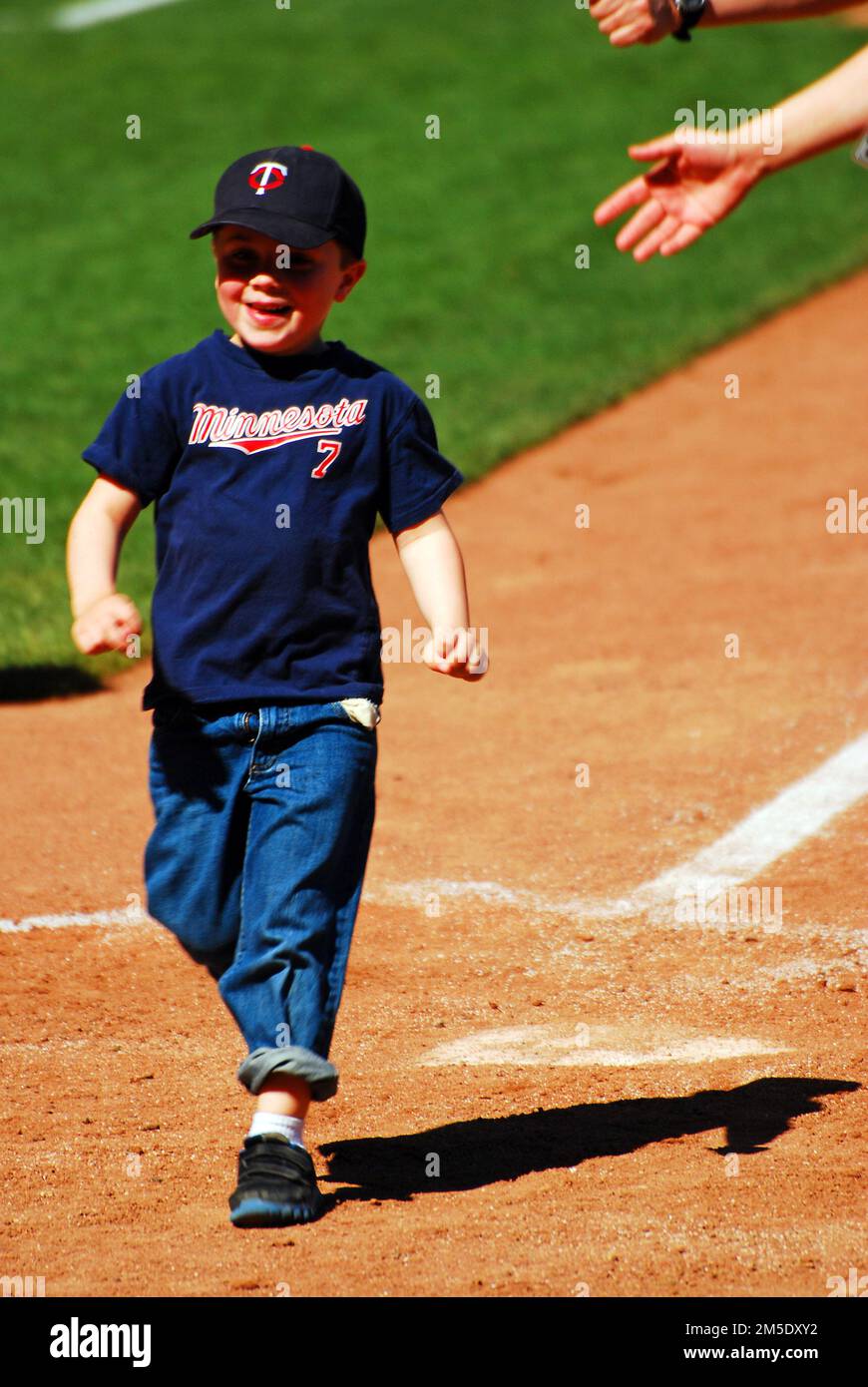 Ein fröhlicher, lächelnder Junge läuft während eines Nachspiellaufs um die Basen im Target Field, Heimstadion der Minnesota Twins Stockfoto