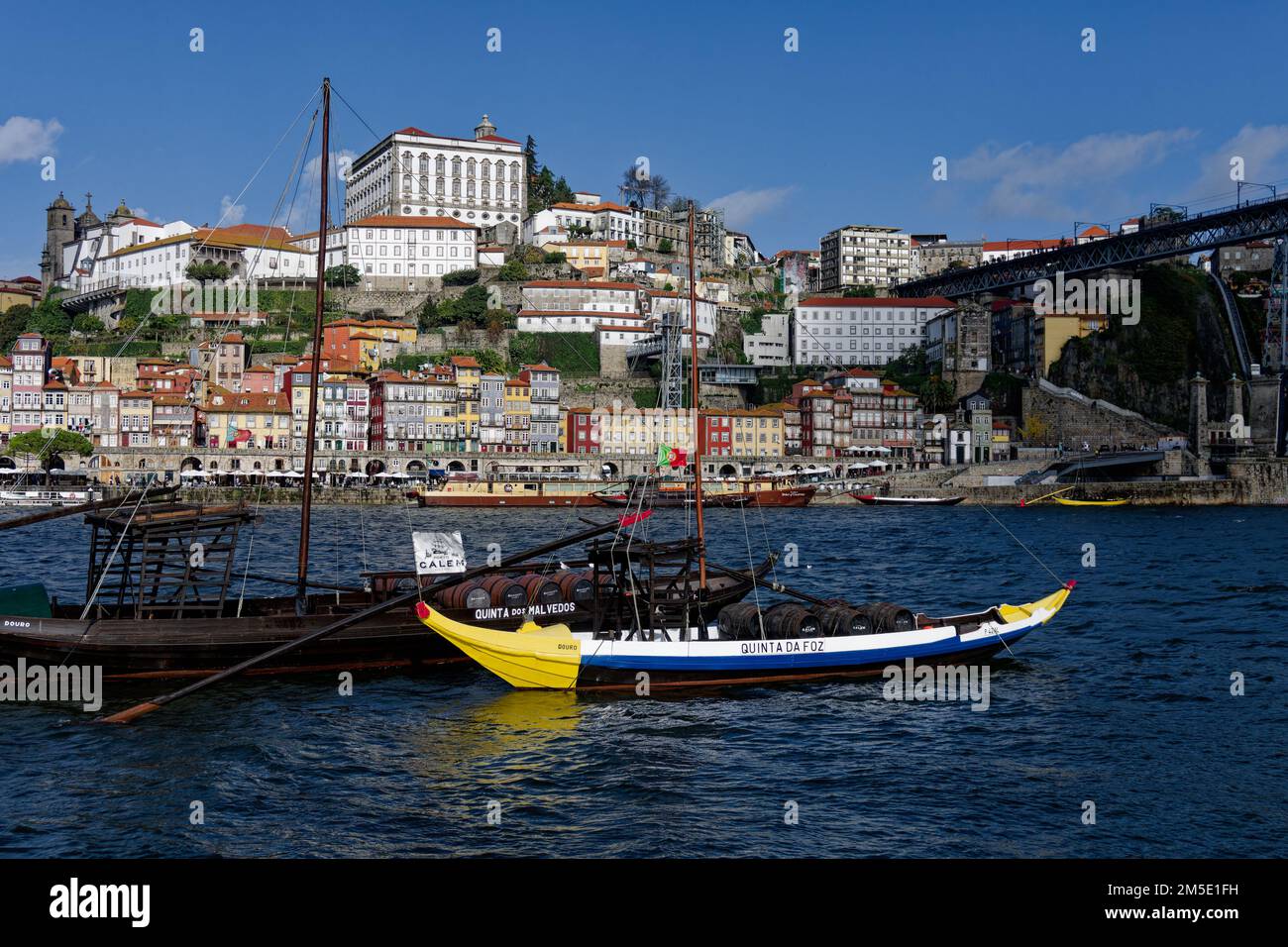 Boote auf dem Fluss Douro mit Fässern Portwein, die für Graham's und Calem Porto, Portugal, Europa und die Altstadt im Hintergrund werben. Stockfoto