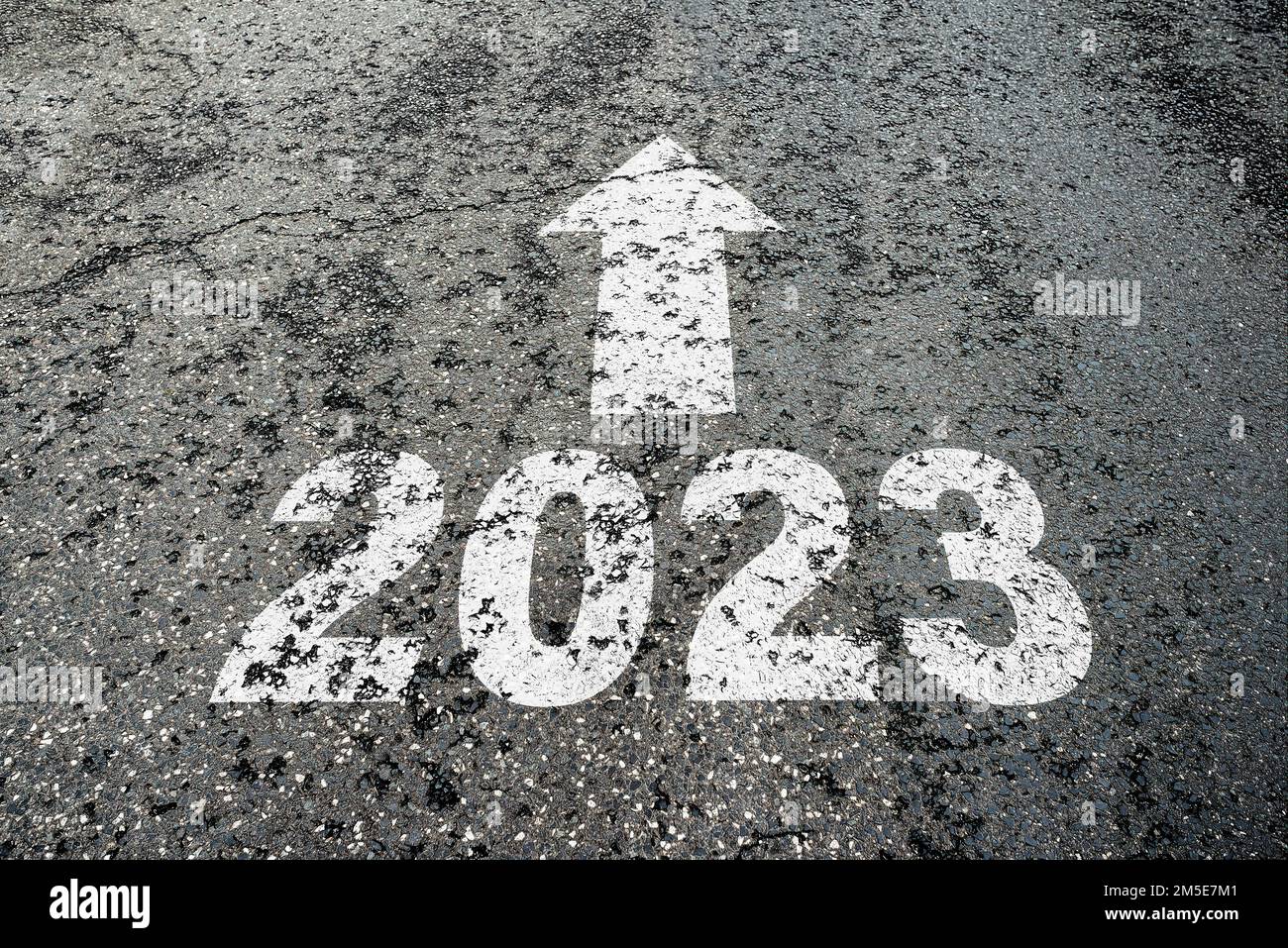 Nummer 2023 und Pfeil zeigen auf gebrochenen Asphalt, Neujahrsrichtung und Erwartungskonzept Stockfoto