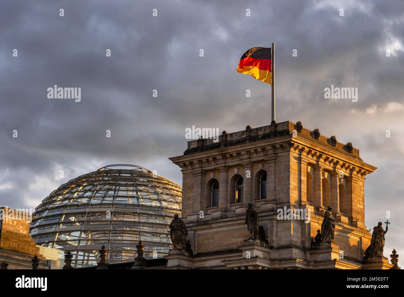 Der Reichstagsdom und die Nationalflagge Deutschlands bei Sonnenuntergang in der Stadt Berlin. Stockfoto