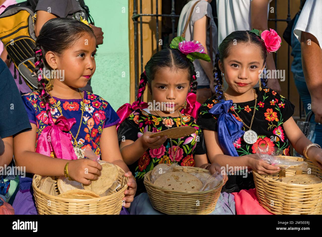 Drei kleine Mädchen in typischen Kleidern aus dem Isthmus von Tehuantepec warten auf eine Parade beim Guelaguetza Festival in Oaxaca, Mexiko. Stockfoto