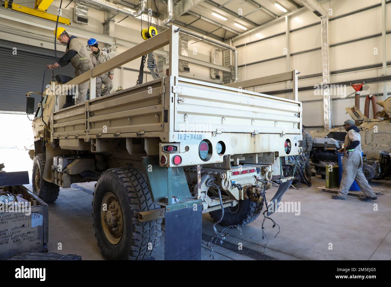 USA Soldaten und zivile Auftragnehmer bereiten sich darauf vor, das Bett des M1078 Light Medium Tactical Vehicle (LMTV) zu entfernen, um Reparaturen am Fahrzeug in der Wartungsbucht in Drawsko Pomorskie, Polen, am 2. März 2022 durchzuführen. Sie reparierten und führten vorbeugende Wartungsarbeiten an den Fahrzeugen durch, um sicherzustellen, dass sie einsatzfähig sind. Stockfoto