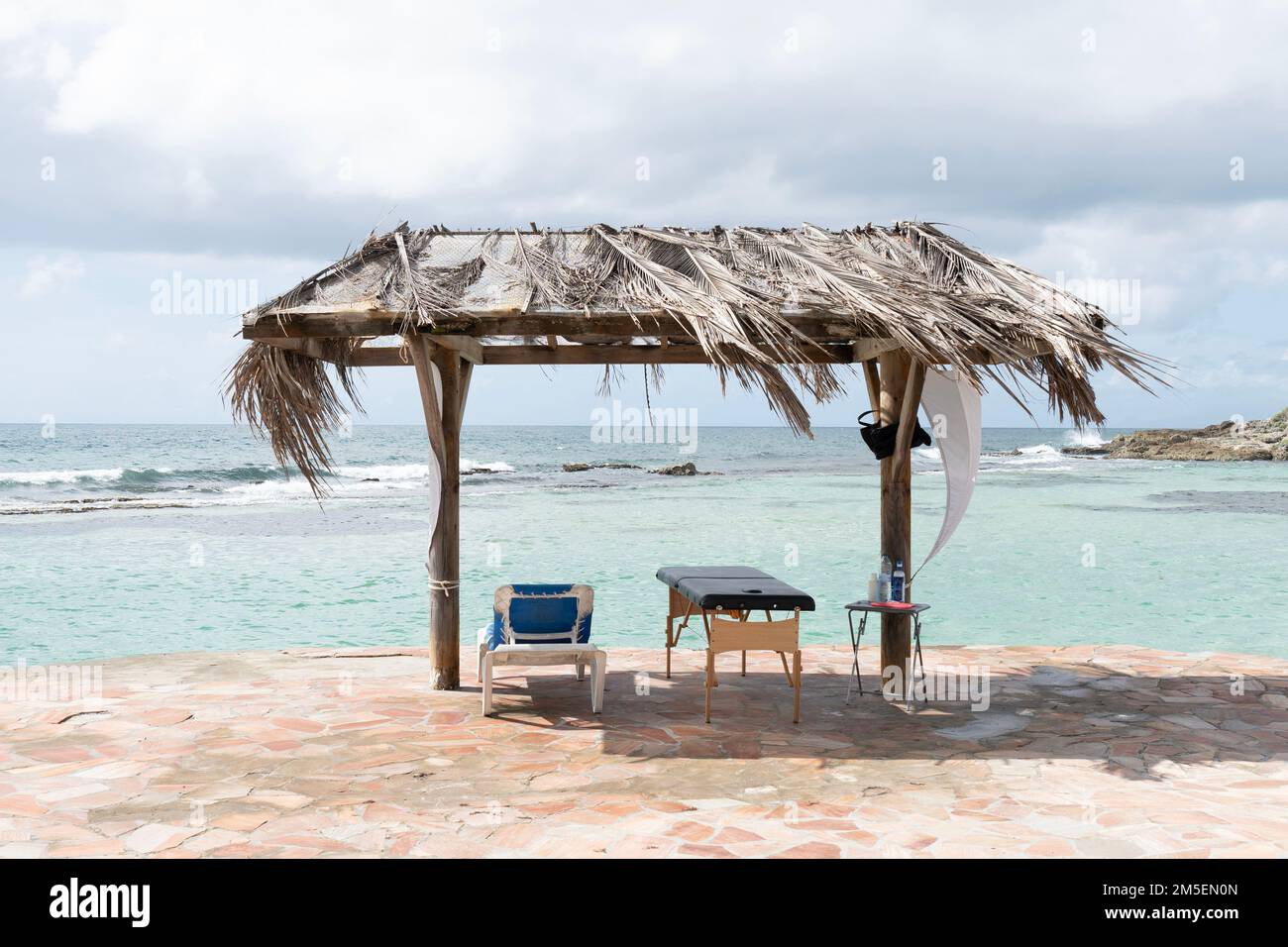 Holzdach mit Palmenblattdach am Strand am Meer. Stuhl und Massage schlecht zum Entspannen Stockfoto