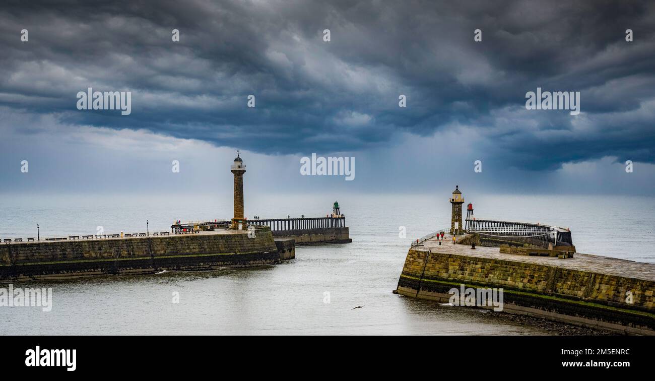 Ein Sturm am Horizont mit Blick auf zwei Piers in Whitby Stockfoto
